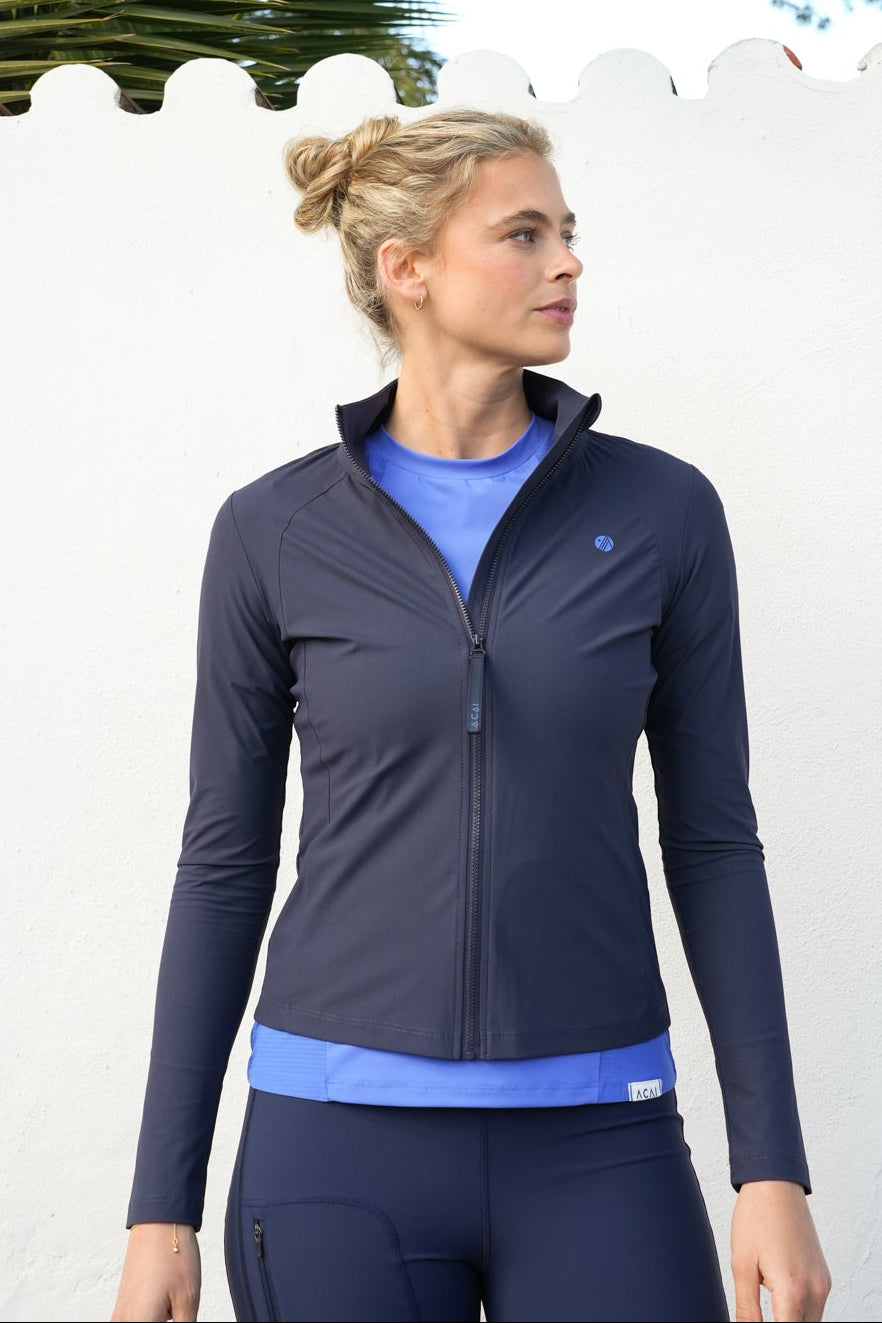 Woman wearing a blue athletic outfit standing outdoors with palm trees in the background