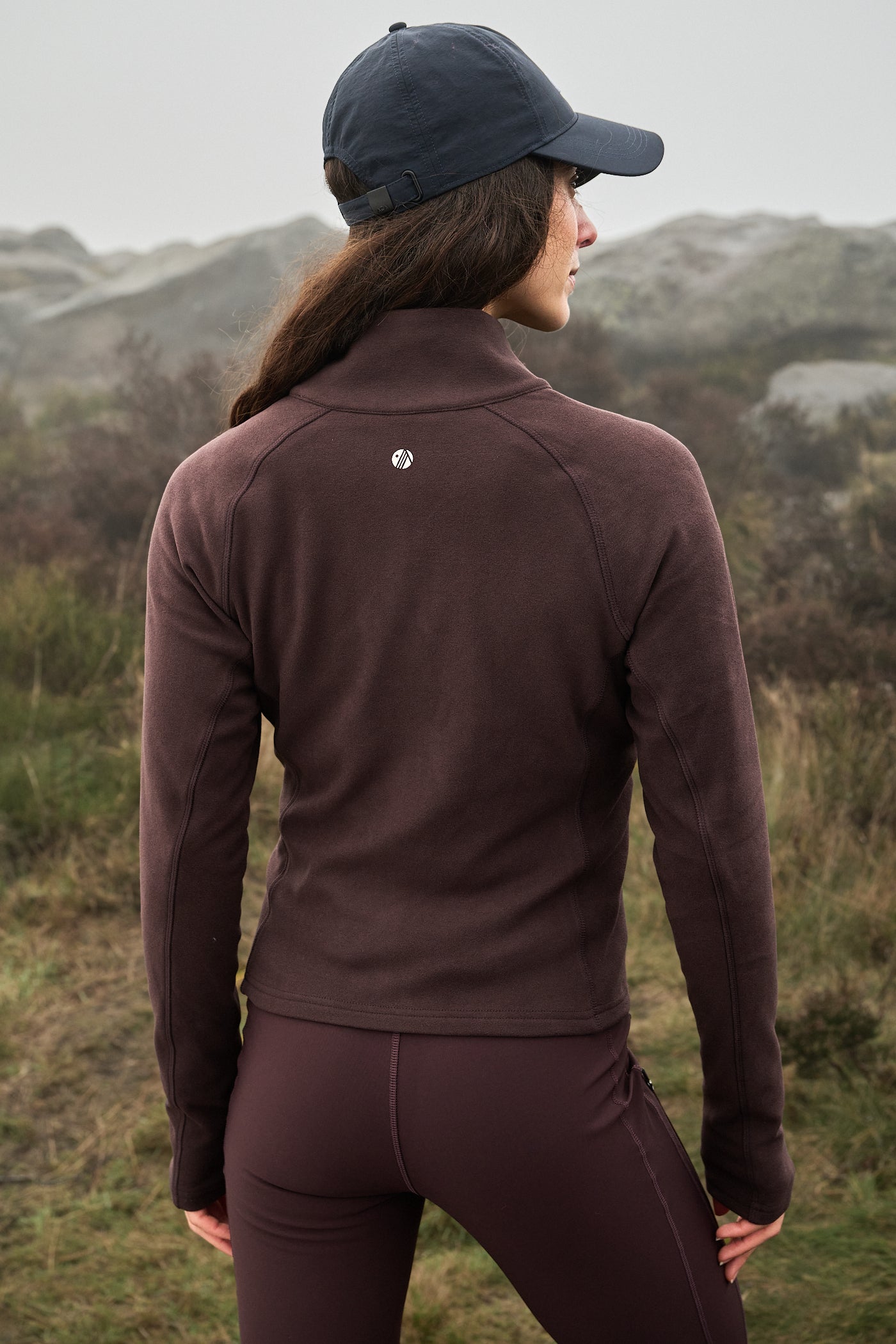 Person wearing a brown jacket and cap in a natural setting