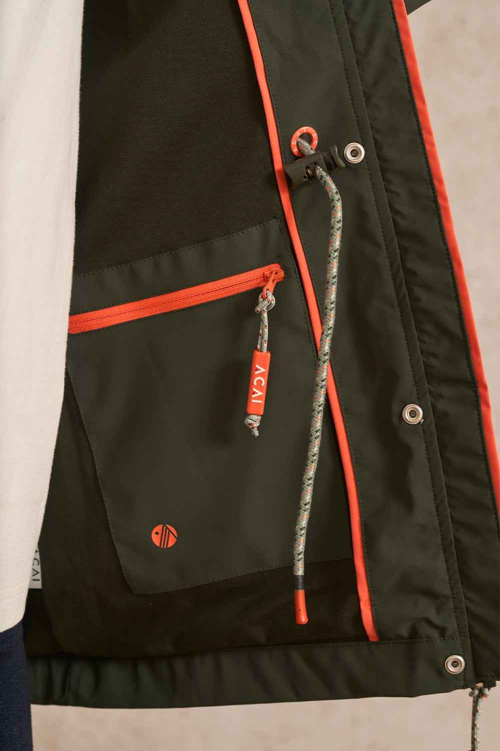 Close-up of a black jacket with bright orange piping and zipper accents, featuring a front zip pocket with an orange zipper pull and a hanging drawstring with a small orange A41 tag.